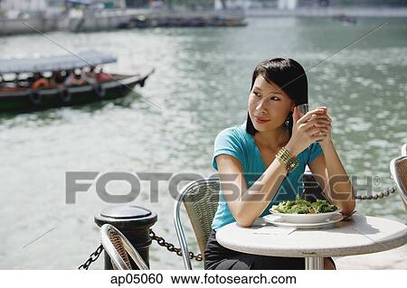 Young woman sitting at riverside cafe, looking away, smiling View Large Photo Image Stock Image - Young woman sitting at riverside cafe, looking away, smiling. Fotosearch