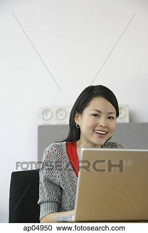 Young woman using laptop, smiling at camera View Large Photo Image Stock Image - Young woman using laptop, smiling at camera. Fotosearch