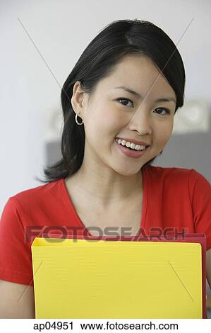 Young woman with folders, smiling at camera View Large Photo Image Stock Image - Young woman with folders, smiling at camera. Fotosearch