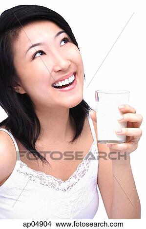 Picture - Young woman with glass of milk, looking up. Fotosearch