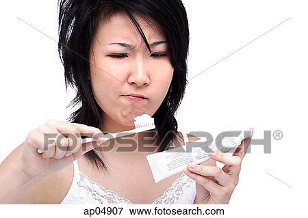Stock Photo - Young woman with tousled hair, holding toothbrush and toothpaste. Fotosearch