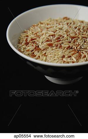 Picture - Bowl of uncooked rice against black background. Fotosearch