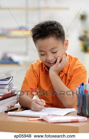 Boy doing homework, hand on chin View Large Photo Image Stock Photo - Boy doing homework, hand on chin. Fotosearch