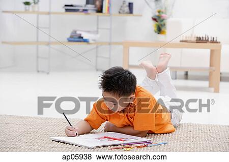 Boy lying on floor with sketch pad View Large Photo Image Stock Photo - Boy lying on floor with sketch pad. Fotosearch