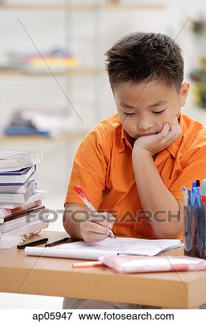 Boy sitting at desk, doing homework View Large Photo Image Stock Photo - Boy sitting at desk, doing homework. Fotosearch