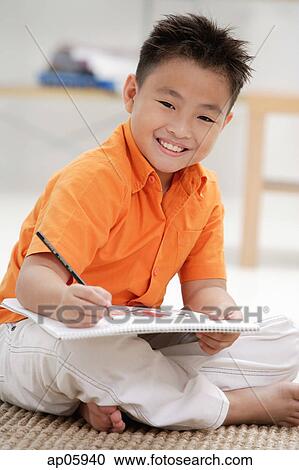 Stock Image - Boy with sketch pad, smiling at camera. Fotosearch