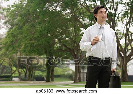 Stock Image - Businessman carrying briefcase and Styrofoam cup. Fotosearch