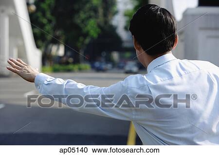 Stock Image - Businessman flagging a cab. Fotosearch