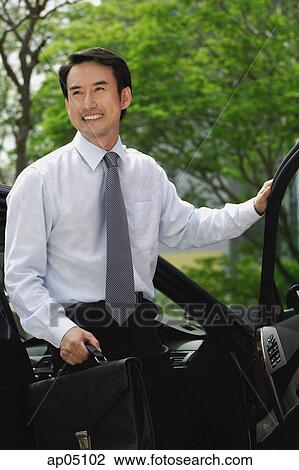 Stock Image - Businessman getting out of car, carrying briefcase. Fotosearch