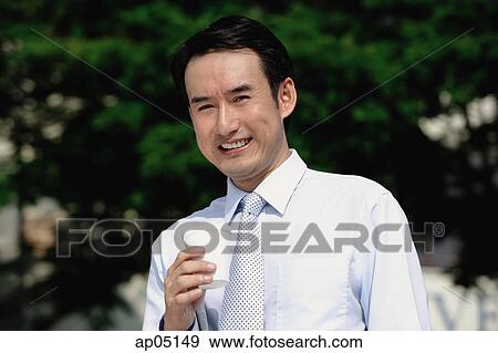 Businessman holding disposable cup, smiling at camera View Large Photo Image Stock Photo - Businessman holding disposable cup, smiling at camera. Fotosearch