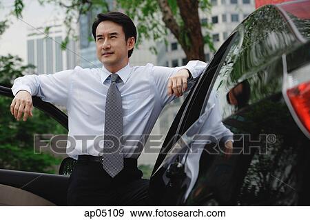 Stock Photo - Businessman leaning on car. Fotosearch