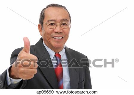 Stock Image - Businessman looking at camera, making thumbs up sign. Fotosearch