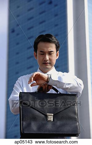 Businessman looking at watch, frowning View Large Photo Image Stock Image - Businessman looking at watch, frowning. Fotosearch