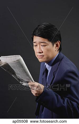 Stock Photo - Businessman reading newspaper, studio shot. Fotosearch
