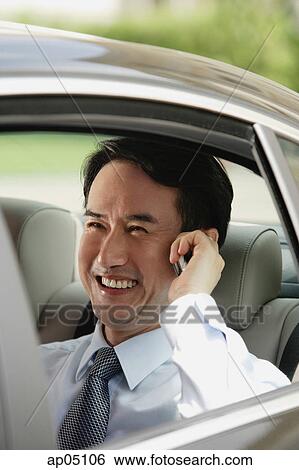 Businessman sitting in car, using mobile phone View Large Photo Image Stock Photograph - Businessman sitting in car, using mobile phone. Fotosearch