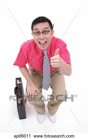 Stock Image - Businessman sitting on chair, smiling at camera, making a thumbs up sign. Fotosearch