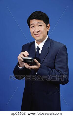 Businessman standing, holding calculator View Large Photo Image Stock Image - Businessman standing, holding calculator. Fotosearch