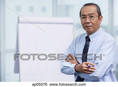 Stock Photograph - Businessman standing in front of flip board, portrait. Fotosearch