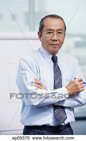 Businessman standing in front of flipchart, arms crossed View Large Photo Image Stock Photography - Businessman standing in front of flipchart, arms crossed. Fotosearch