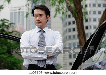 Businessman standing next to car, arms crossed View Large Photo Image Stock Photo - Businessman standing next to car, arms crossed. Fotosearch