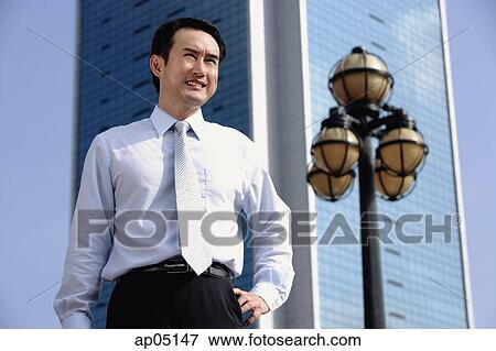 Businessman standing with hand on hip, looking away View Large Photo Image Stock Photo - Businessman standing with hand on hip, looking away. Fotosearch