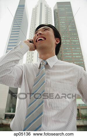 Businessman using mobile phone, buildings in the background View Large Photo Image Stock Photograph - Businessman using mobile phone, buildings in the background. Fotosearch