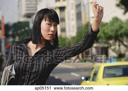 Stock Image - Businesswoman hailing a taxi. Fotosearch