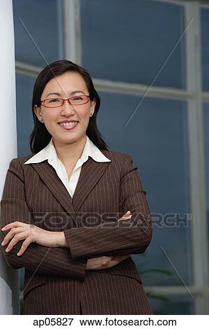 Businesswoman leaning on wall, arms crossed, smiling View Large Photo Image Stock Photo - Businesswoman leaning on wall, arms crossed, smiling. Fotosearch