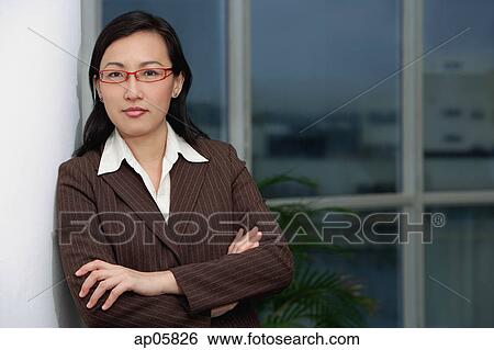 Stock Photograph - Businesswoman leaning on wall, arms crossed. Fotosearch