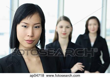Businesswoman looking at camera, other women behind her View Large Photo Image Stock Photo - Businesswoman looking at camera, other women behind her. Fotosearch