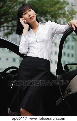 Stock Photo - Businesswoman using mobile phone, hand on hip. Fotosearch