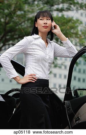 Businesswoman using mobile phone, hand on hip, leaning on car door View Large Photo Image Stock Photo - Businesswoman using mobile phone, hand on hip, leaning on car door. Fotosearch
