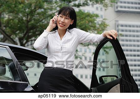 Businesswoman using mobile phone, leaning on car door View Large Photo Image Stock Photo - Businesswoman using mobile phone, leaning on car door. Fotosearch