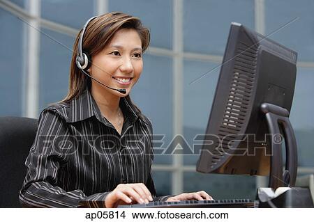 Businesswoman with hands free device, using computer View Large Photo Image Picture - Businesswoman with hands free device, using computer. Fotosearch