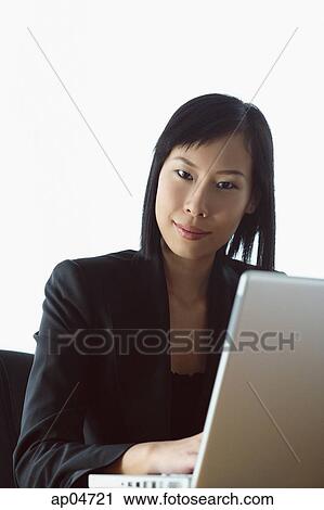 Stock Image - Businesswoman with laptop, looking at camera. Fotosearch