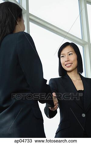 Businesswomen shaking hands, low angle view View Large Photo Image Stock Image - Businesswomen shaking hands, low angle view. Fotosearch