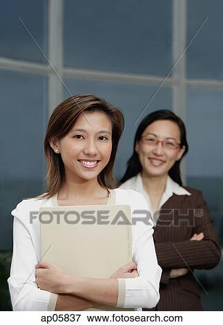 Stock Photo - Businesswomen smiling at camera, focus on the foreground. Fotosearch