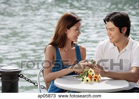 Couple at outdoor cafe, man giving woman a gift View Large Photo Image Stock Image - Couple at outdoor cafe, man giving woman a gift. Fotosearch