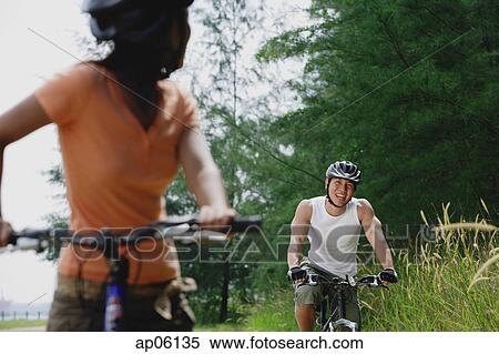 Couple cycling, focus on man in background View Large Photo Image Stock Photography - Couple cycling, focus on man in background. Fotosearch