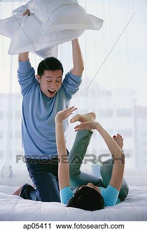 Couple in bedroom having a pillow fight, woman lying on back View Large Photo Image Stock Image - Couple in bedroom having a pillow fight, woman lying on back. Fotosearch