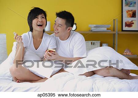 Couple in bedroom, woman opening present View Large Photo Image Stock Photography - Couple in bedroom, woman opening present. Fotosearch