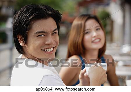 Couple in cafe having coffee, focus on man in foreground, smiling at camera View Large Photo Image Picture - Couple in cafe having coffee, focus on man in foreground, smiling at camera. Fotosearch