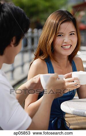 Couple in cafe having coffee, focus on woman smiling at camera View Large Photo Image Stock Image - Couple in cafe having coffee, focus on woman smiling at camera. Fotosearch