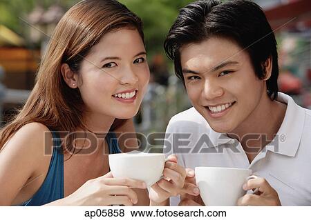 Couple in cafe having coffee, smiling at camera View Large Photo Image Stock Photo - Couple in cafe having coffee, smiling at camera. Fotosearch