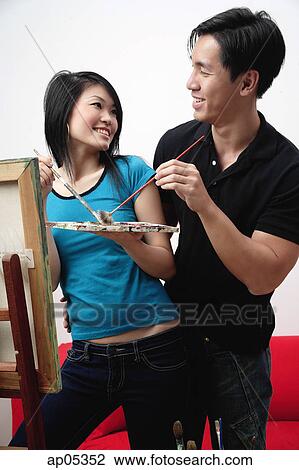 Stock Image - Couple in front of painting easel, looking at each other. Fotosearch