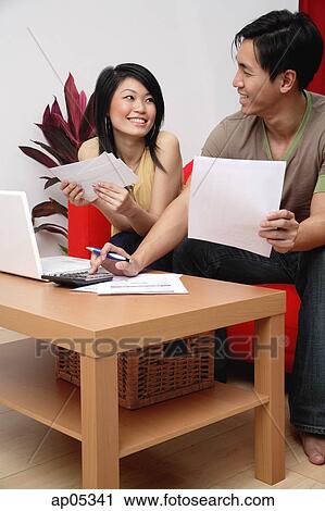 Stock Image - Couple in living room, doing finances. Fotosearch