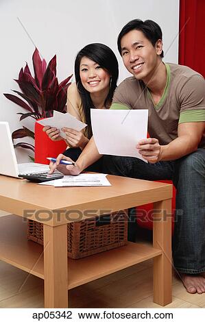 Couple in living room, doing finances, smiling at camera View Large Photo Image Stock Image - Couple in living room, doing finances, smiling at camera. Fotosearch