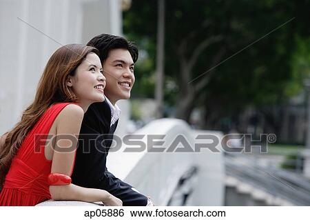 Couple leaning over bridge railing, looking away View Large Photo Image Stock Photograph - Couple leaning over bridge railing, looking away. Fotosearch