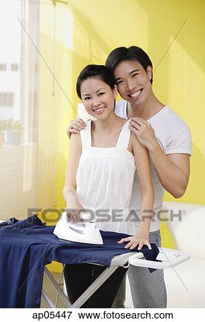 Couple looking at camera, woman ironing, man next to her View Large Photo Image Stock Photo - Couple looking at camera, woman ironing, man next to her. Fotosearch