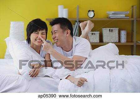 Couple lying on bed, man touching woman's nose View Large Photo Image Stock Image - Couple lying on bed, man touching woman's nose. Fotosearch